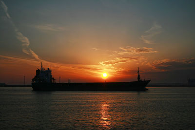 Silhouette ship in sea against sky during sunset