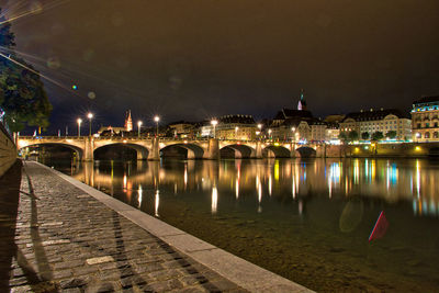 Illuminated bridge over river against sky at night