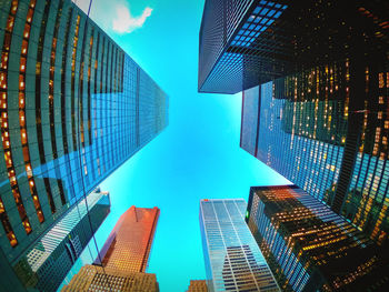 Directly below shot of modern buildings against blue sky