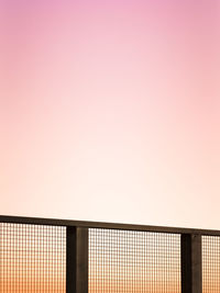 Metallic fence against clear sky during sunset