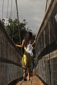 Rear view of woman standing on bridge