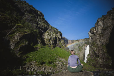 Rear view of woman looking at waterfall in mountains