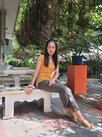 Low angle view of young woman standing against trees