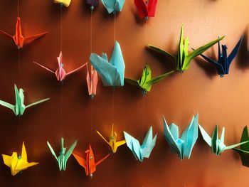 Colorful paper cranes hanging against wall