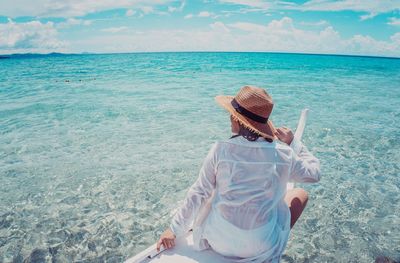 Rear view of woman on beach against sky