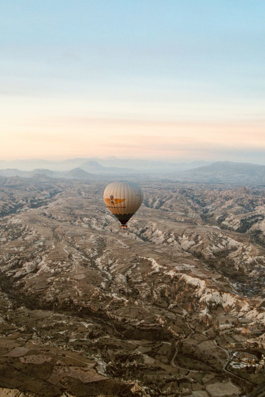 AERIAL VIEW OF HOT AIR BALLOON FLYING OVER MOUNTAIN