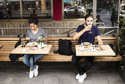 Full length of man and woman having lunch at sidewalk cafe