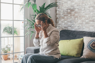 Young woman using phone while sitting on sofa at home