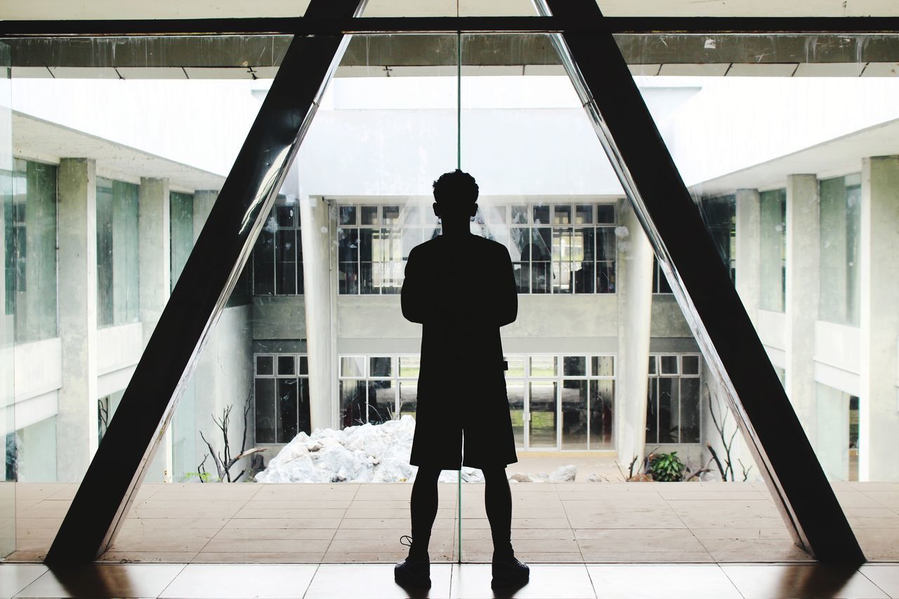 REAR VIEW OF SILHOUETTE MAN STANDING AGAINST BUILDING