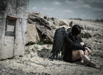 Woman wearing wings trapped with chain on land