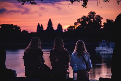 Rear view of women standing against sky during sunset