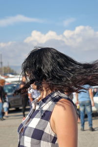 Woman tossing hair against sky