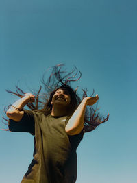 Low angle view of smiling man against clear blue sky
