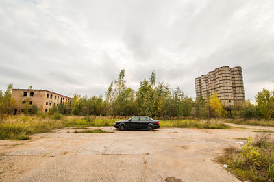 Car on road by buildings against sky