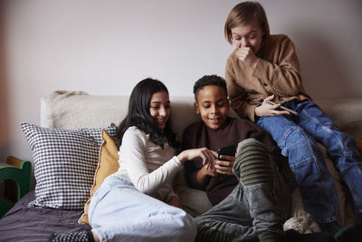 Children sitting on bed and using phones