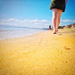 Low section of man walking on beach