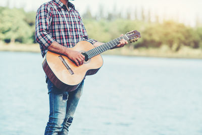 Midsection of man playing guitar