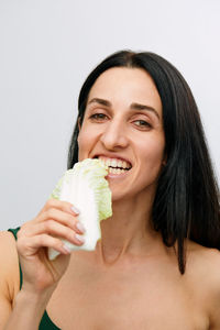 Woman biting lettuce against white background