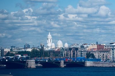 View of buildings at waterfront against cloudy sky