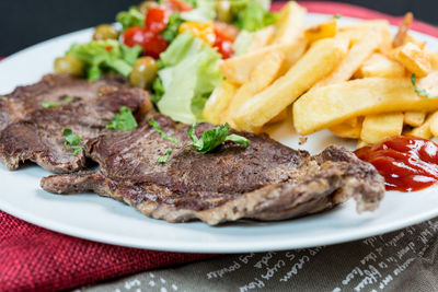 Beefsteak and french fries with salad and sauce served in plate