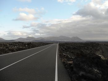 Road leading towards mountains against sky