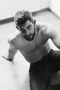 High angle view portrait of shirtless man sitting on floor at home