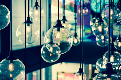 Close-up of illuminated light bulbs hanging by window