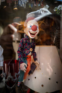 A clown puppet hangs in a shop window