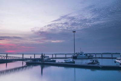 View of boats moored at harbor against cloudy sky