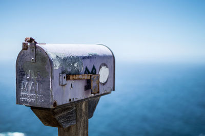 Close-up of public mailbox against sea