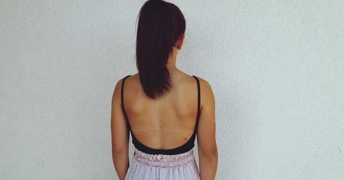 Rear view of woman standing against white wall