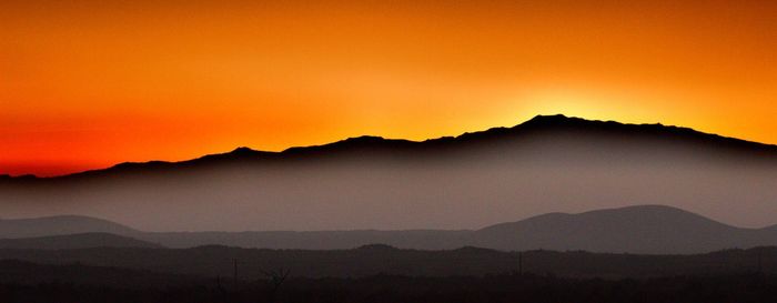 Scenic view of mountains against orange sky