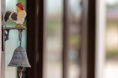 Close-up of rooster figurine on bell