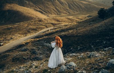 Rear view of woman sitting on rock