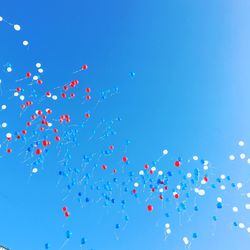 Low angle view of balloons flying against blue sky