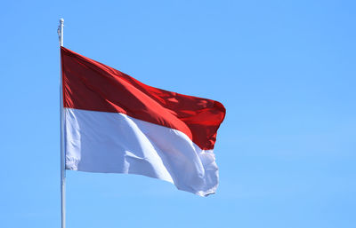 Low angle view of flag against clear blue sky