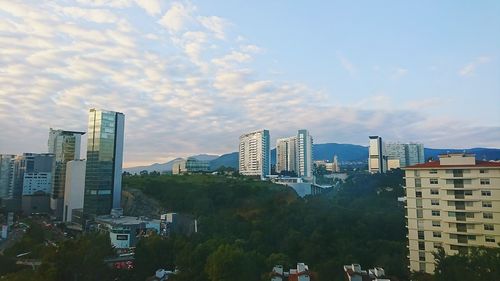 View of buildings in city against cloudy sky