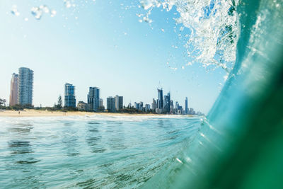 Sea by buildings in city against sky