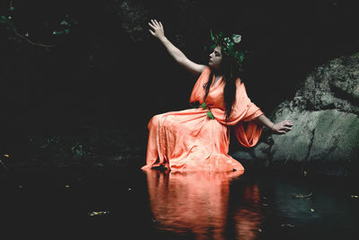 Woman sitting on rock by lake