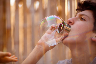 Boy blowing bubbles while standing outdoors