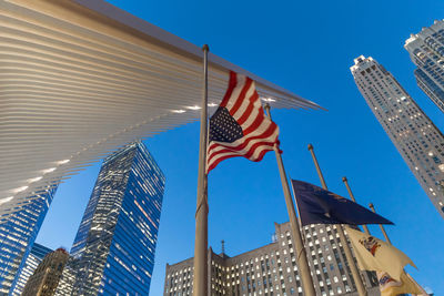 Low angle view of flags against modern buildings against sky