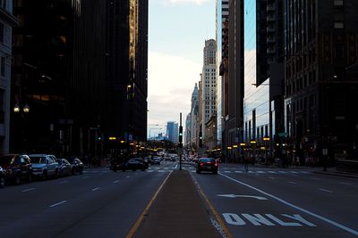 Cars on street in city against sky