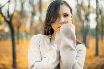 Young woman standing against trees