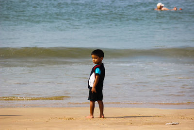 Full length of cute boy standing on shore at beach