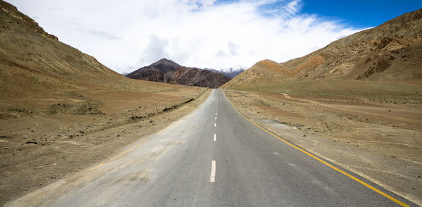 Empty road in desert against sky