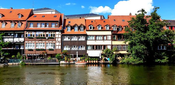 Buildings by river against sky