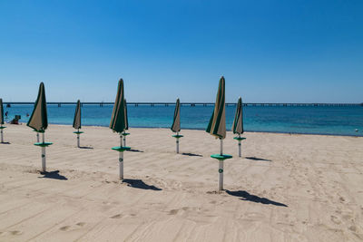 Wooden posts on beach against clear blue sky