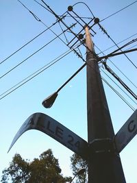 Low angle view of electricity pylon against blue sky