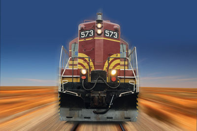 Blurred motion of train on railroad track against blue sky