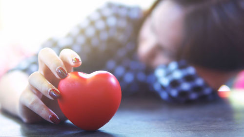 Close-up of depressed holding red heart shape toy on table